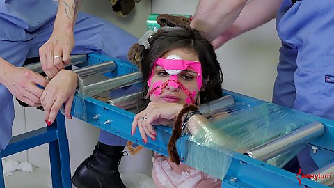 Bondaged with plastic and rope to a ladder Luna Lovely getting mouth stuffed with a pair of dicks and balls while degraded on the floor