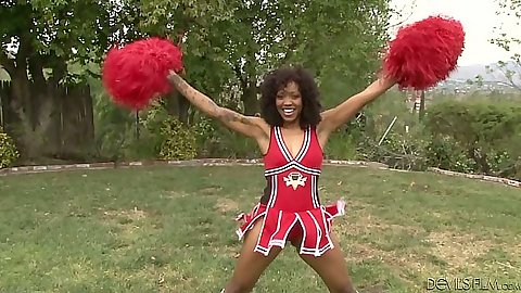 Ebony cheerleader outdoors in uniform with Lotus Lain practicing her moves